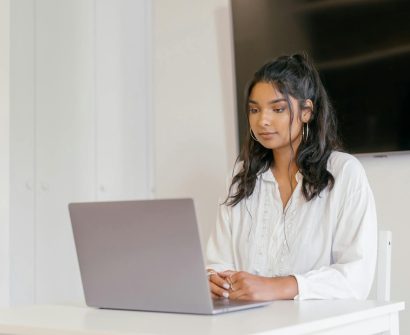 A young woman focused on studying with her laptop in a modern indoor setting.